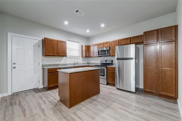 a kitchen with stainless steel appliances granite countertop a refrigerator and a stove top oven