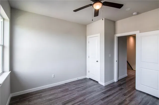 an empty room with wooden floor chandelier fan and closet area