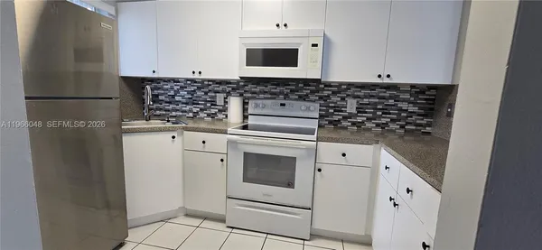 a kitchen with white cabinets and white appliances