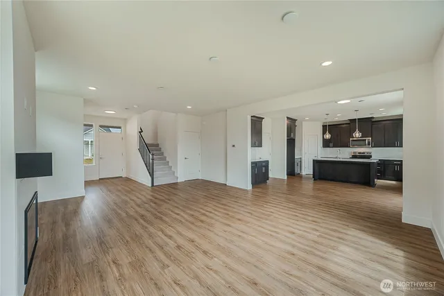 a view of kitchen with kitchen island granite countertop wooden floor and stainless steel appliances
