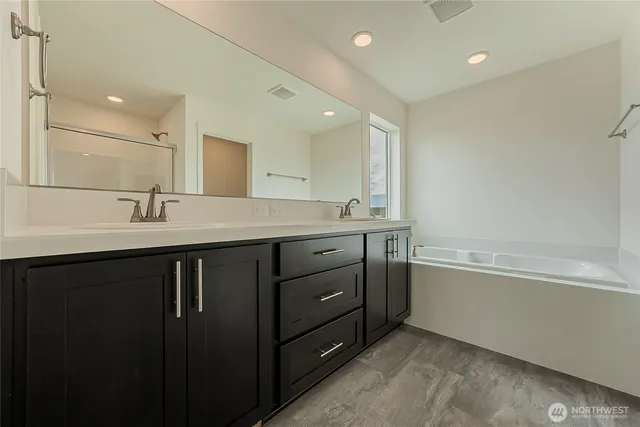 a bathroom with a sink double vanity granite tub and a mirror
