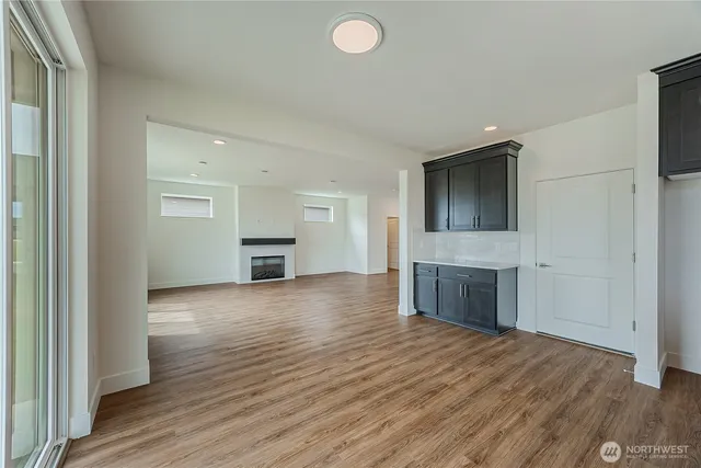 an empty room with wooden floor and a kitchen