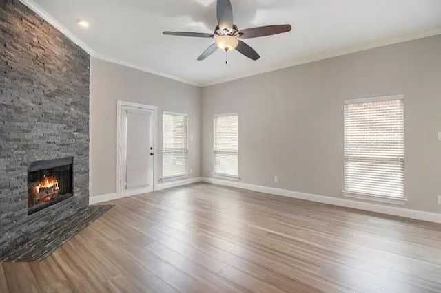 a view of an empty room with wooden floor fireplace and a window