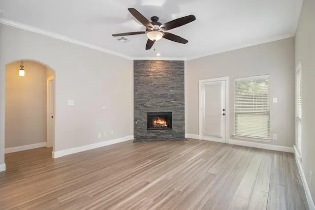 a view of an empty room with wooden floor and a fireplace
