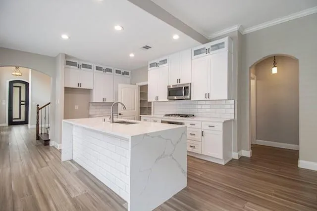 a kitchen with white cabinets appliances and wooden floor
