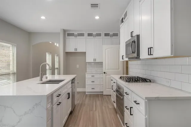 a kitchen with white cabinets and appliances
