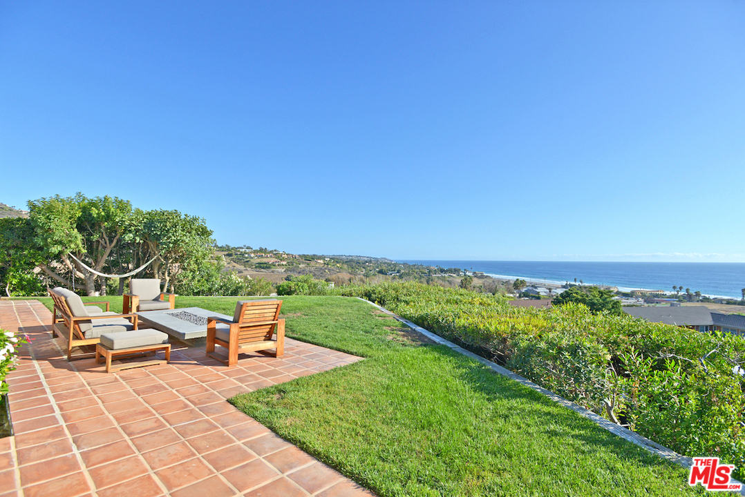 6249 Tapia Drive Malibu, CA 90265 - Photo 1 of 21 a view of a patio with lawn chairs under an umbrella next to a yard