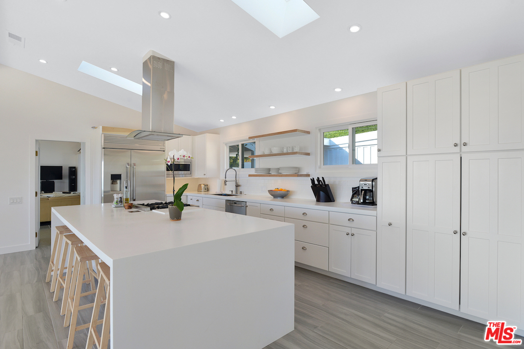 6249 Tapia Drive Malibu, CA 90265 - Photo 2 of 21 a kitchen with sink a stove and white cabinets with wooden floor