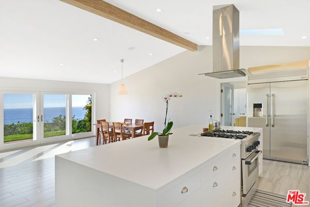 a kitchen with a stove a refrigerator and a dining table with wooden floor