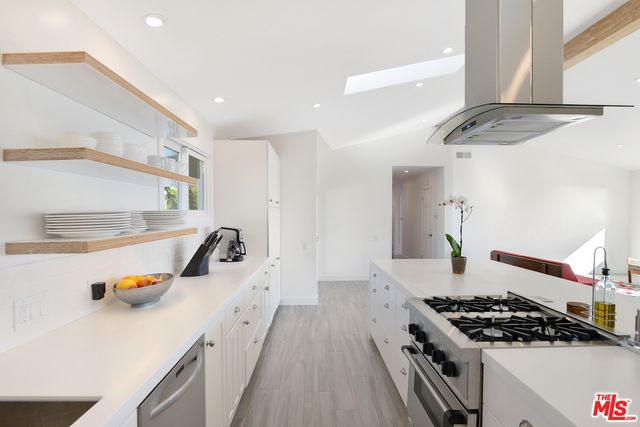 a kitchen with kitchen island stainless steel appliances a sink a stove and a refrigerator