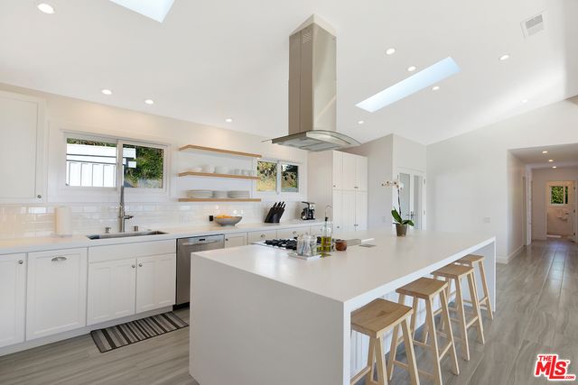 a kitchen with a sink a refrigerator and wooden floor