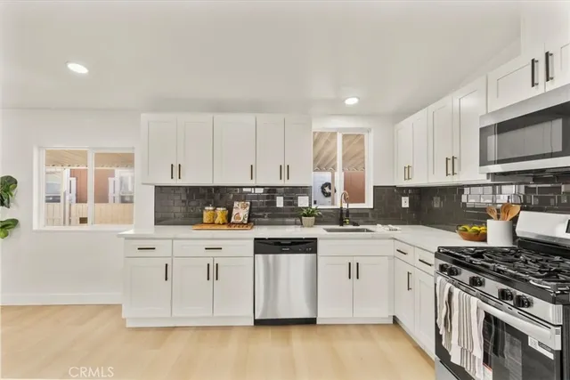 a kitchen with stainless steel appliances granite countertop a stove top oven a sink dishwasher and a refrigerator with wooden floor