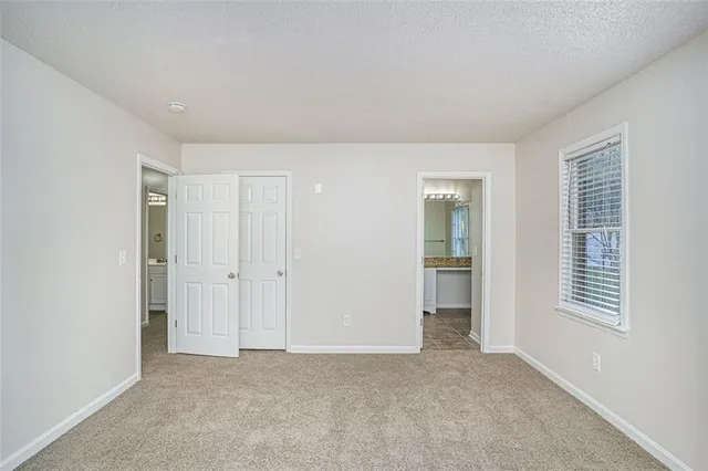 a view of an empty room with closet and a window