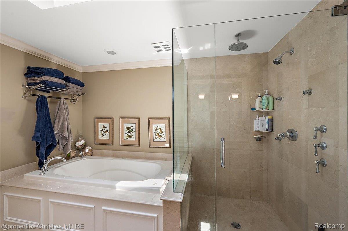 135 Clifton Road Bloomfield Hills, MI 48301 - Photo 43 of 77 Glass-enclosed shower with multiple showerheads and stone-finish tile surround, complemented by a built-in soaking tub with paneled fascia and stone-finish decking