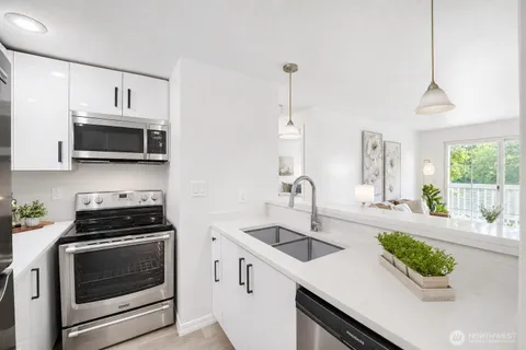 a kitchen with stainless steel appliances a stove a sink a microwave and wooden floor
