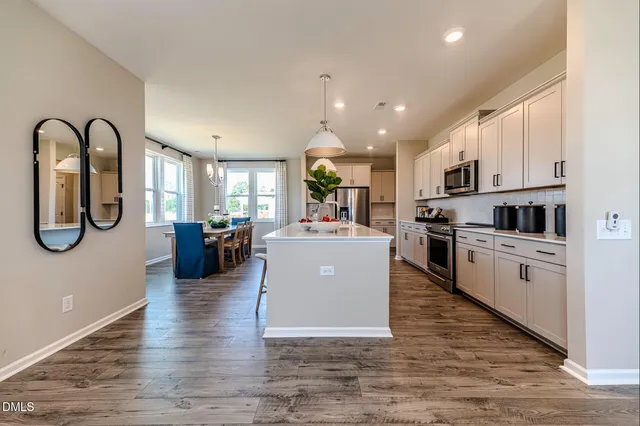 a kitchen with stainless steel appliances granite countertop a refrigerator oven a sink dishwasher and white cabinets with wooden floor