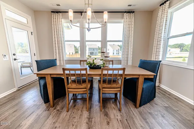 a dining room with wooden floor a chandelier a wooden table and chairs