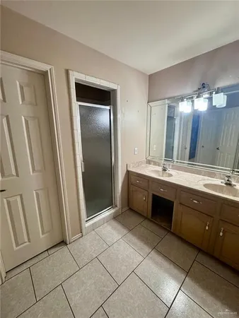 a spacious bathroom with a double vanity sink a mirror and a shower