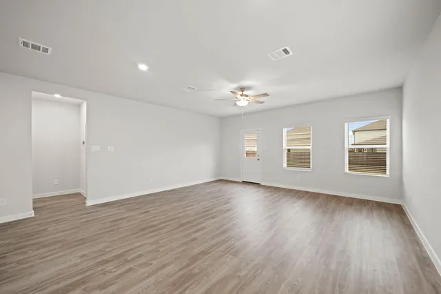 a view of an empty room with wooden floor and window