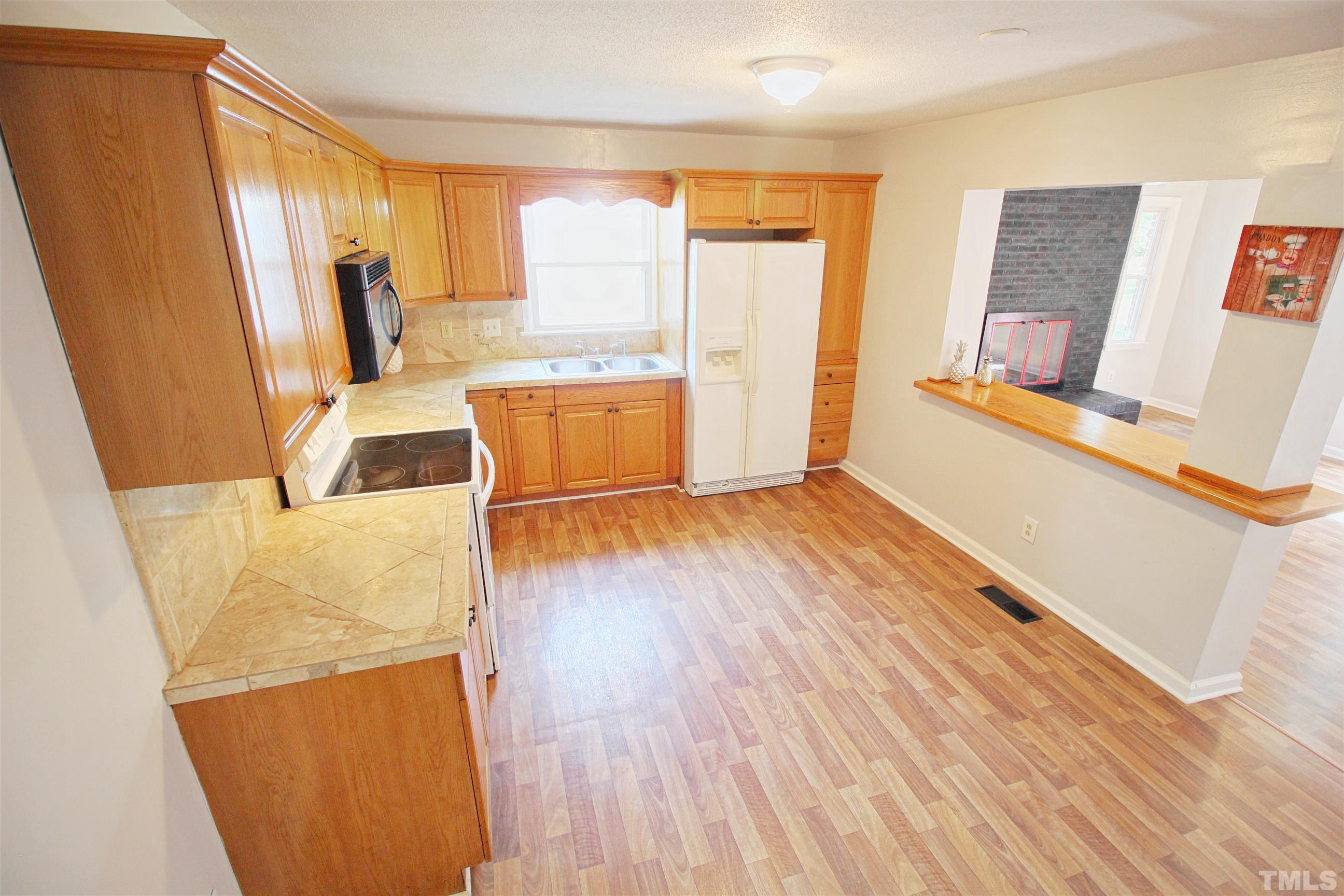 548 Dacian Road Raleigh, NC 27610 - Photo 9 of 16 a view of a kitchen with fridge and wooden floor