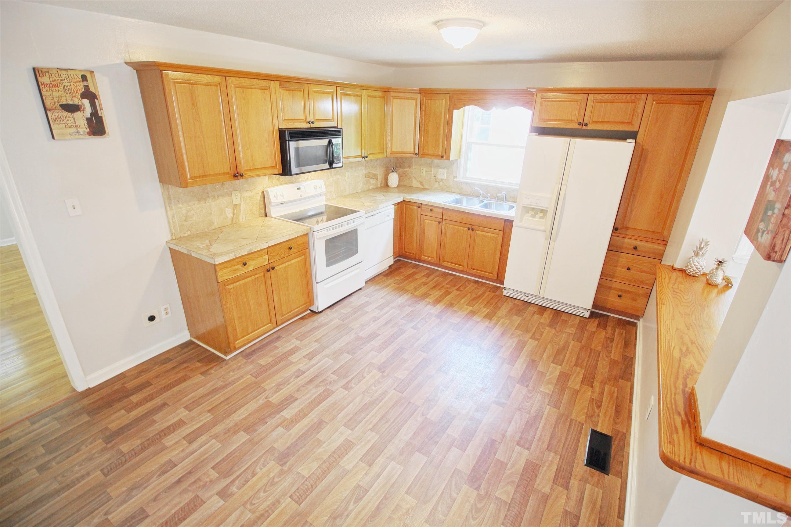 548 Dacian Road Raleigh, NC 27610 - Photo 10 of 16 a kitchen with a sink a refrigerator a window and a counter top space