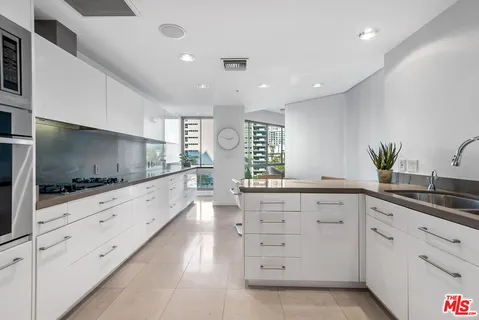 a large kitchen with granite countertop a sink and white cabinets