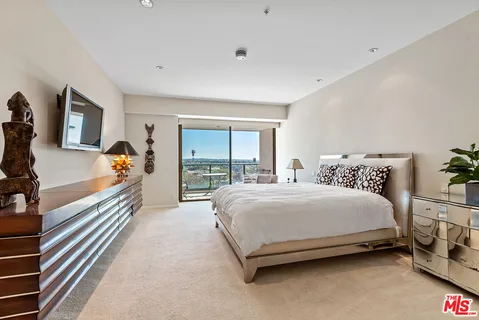 a bedroom with a bed and a flat tv screen on dresser