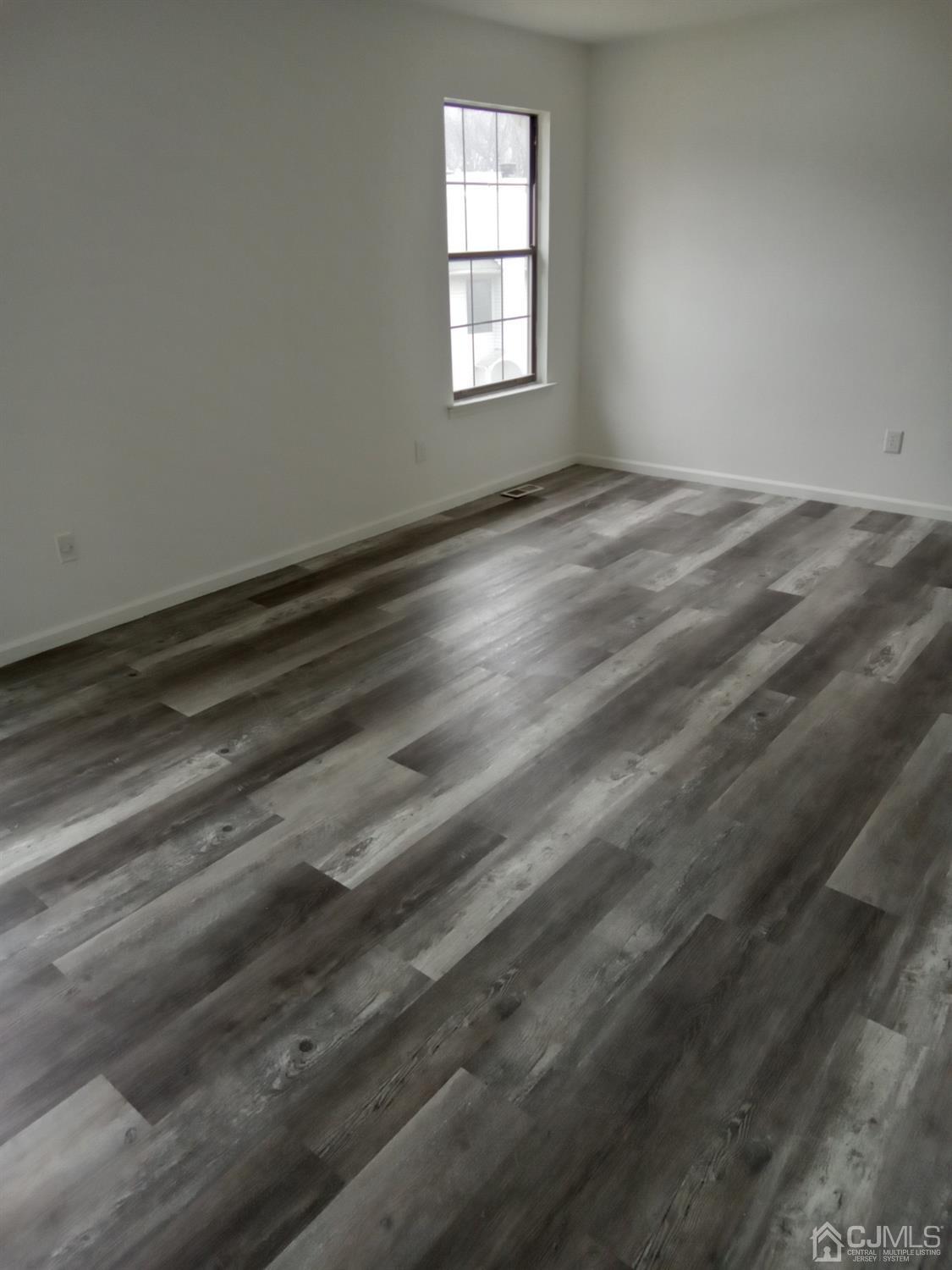 1403 Timber Oaks Road Edison, NJ 08820 - Photo 4 of 6 a view of an empty room with wooden floor and a window