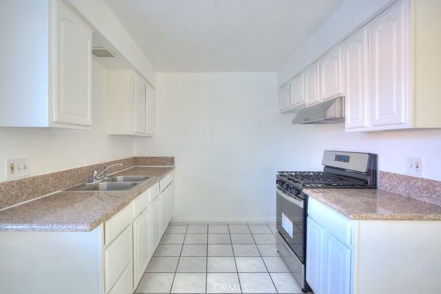 a kitchen with granite countertop a sink stove top oven and cabinets