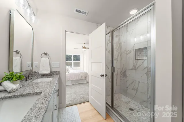 a bathroom with a granite countertop shower a mirror and a sink