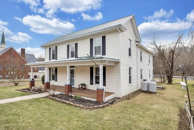 a view of a white house with a yard and couches chairs