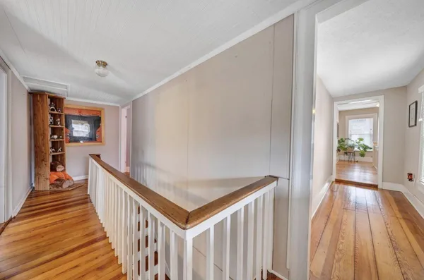a view of a hallway with wooden floor and stairs