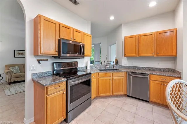 a kitchen with stainless steel appliances granite countertop wooden cabinets a stove top oven a sink and dishwasher