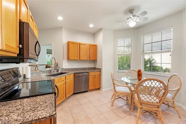 a kitchen with stainless steel appliances granite countertop a sink a stove a dining table and chairs with wooden floor