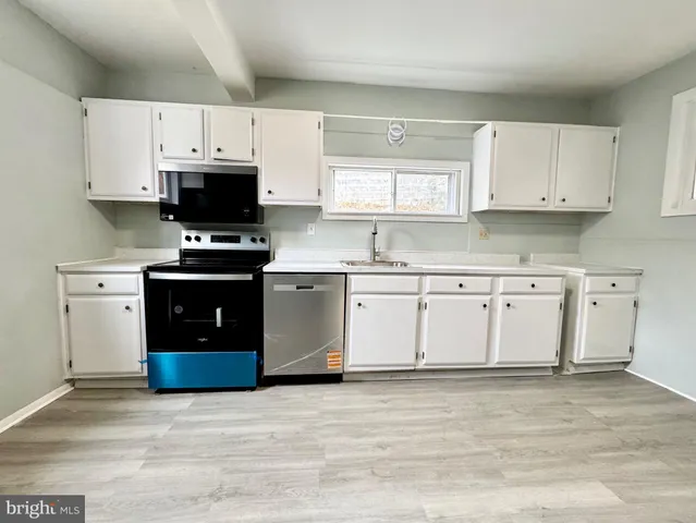 a kitchen with stainless steel appliances granite countertop a stove top oven a sink and white cabinets