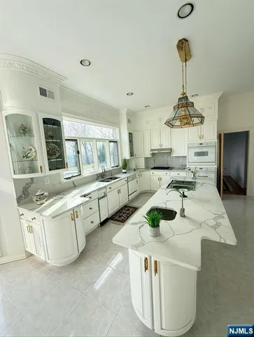 a kitchen with stainless steel appliances a stove a sink a oven a counter top space and living room view