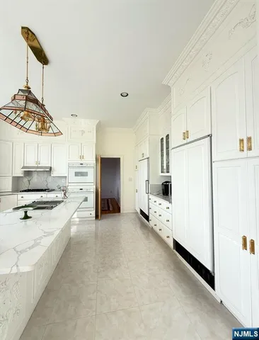 a large white kitchen with a stove a refrigerator and a sink