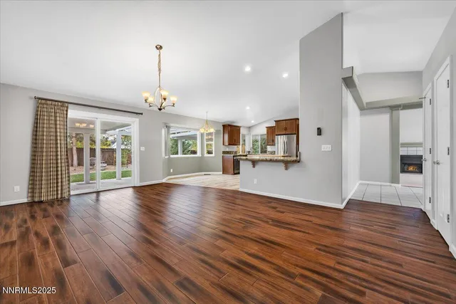 a view of an empty room with wooden floor and a kitchen