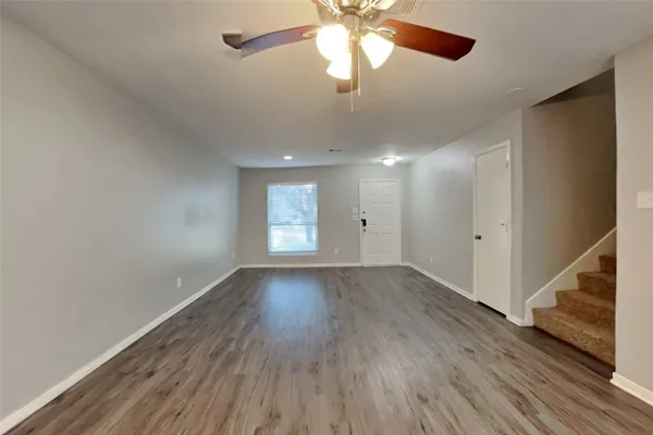 an empty room with wooden floor fan and windows