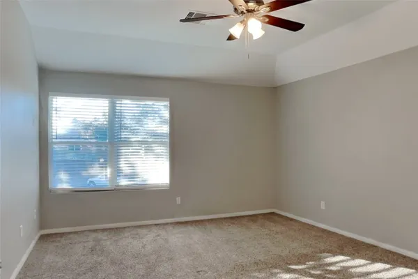 an empty room with a window and a fan