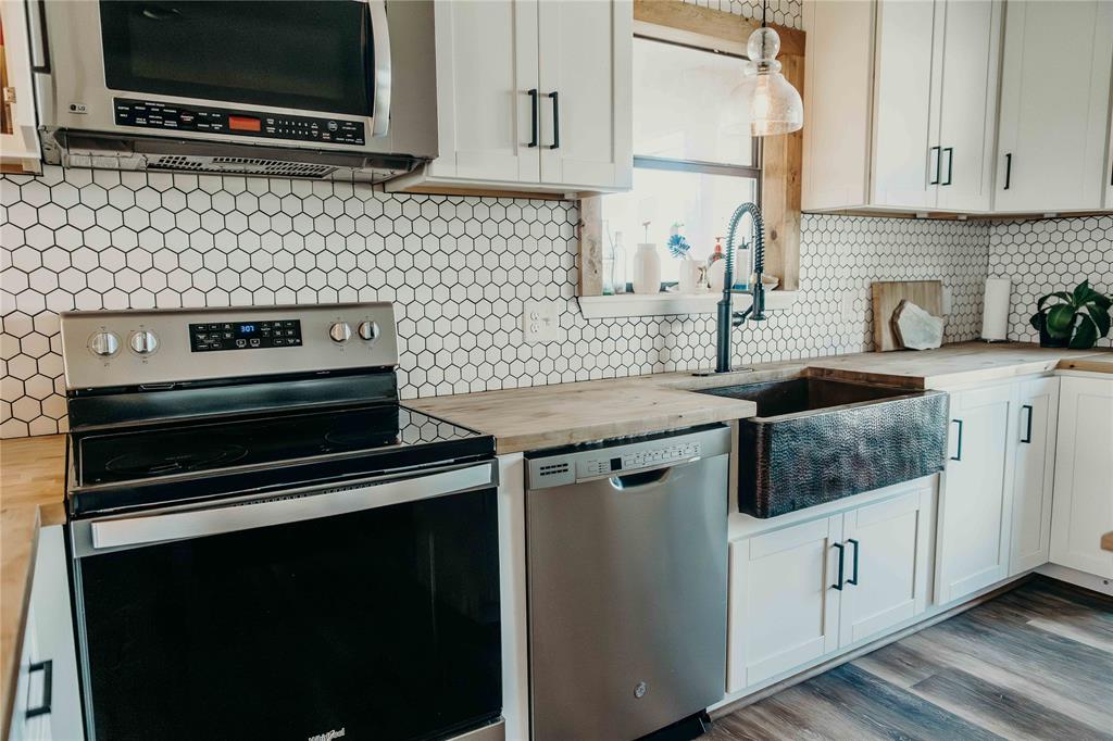 1740 Highway 2247 Comanche, TX 76442 - Photo 13 of 38 Kitchen featuring stainless steel appliances, wood counters, decorative backsplash, and white cabinetry