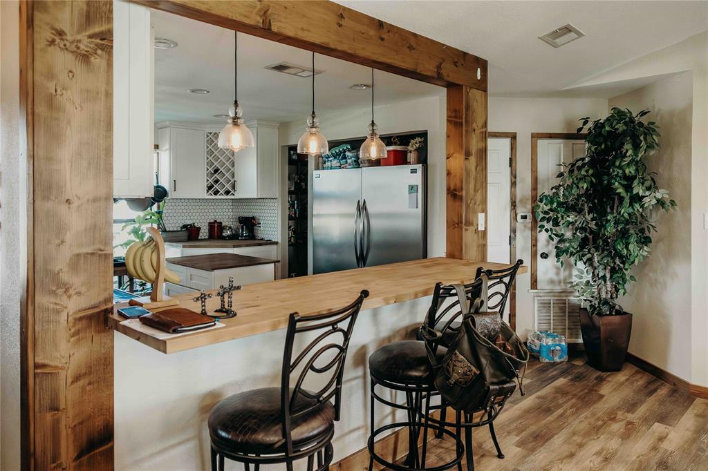 1740 Highway 2247 Comanche, TX 76442 - Photo 7 of 38 Kitchen featuring freestanding refrigerator, tasteful backsplash, butcher block countertops, wood finished floors, and a peninsula