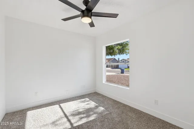 an empty room with a window and a ceiling fan