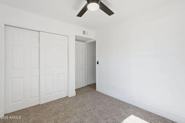 an empty room with a ceiling fan and carpet