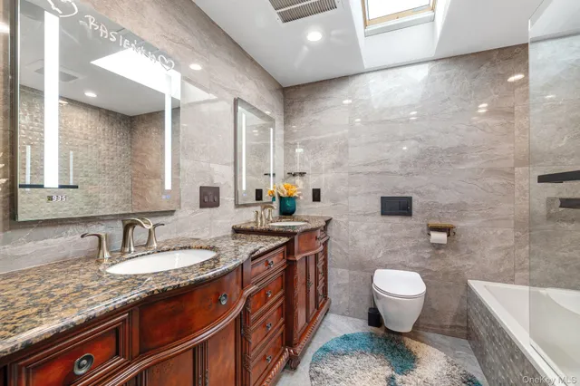 a spacious bathroom with a granite countertop sink a toilet a mirror and bathtub