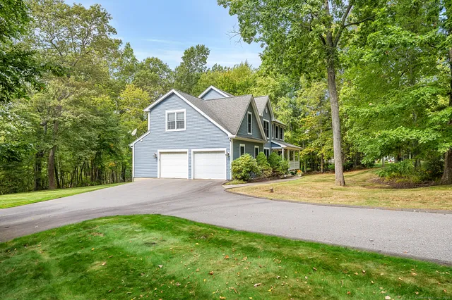 a view of a house with a yard and large trees
