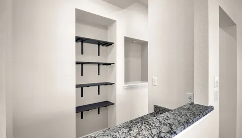 an empty room with chandelier fan and windows