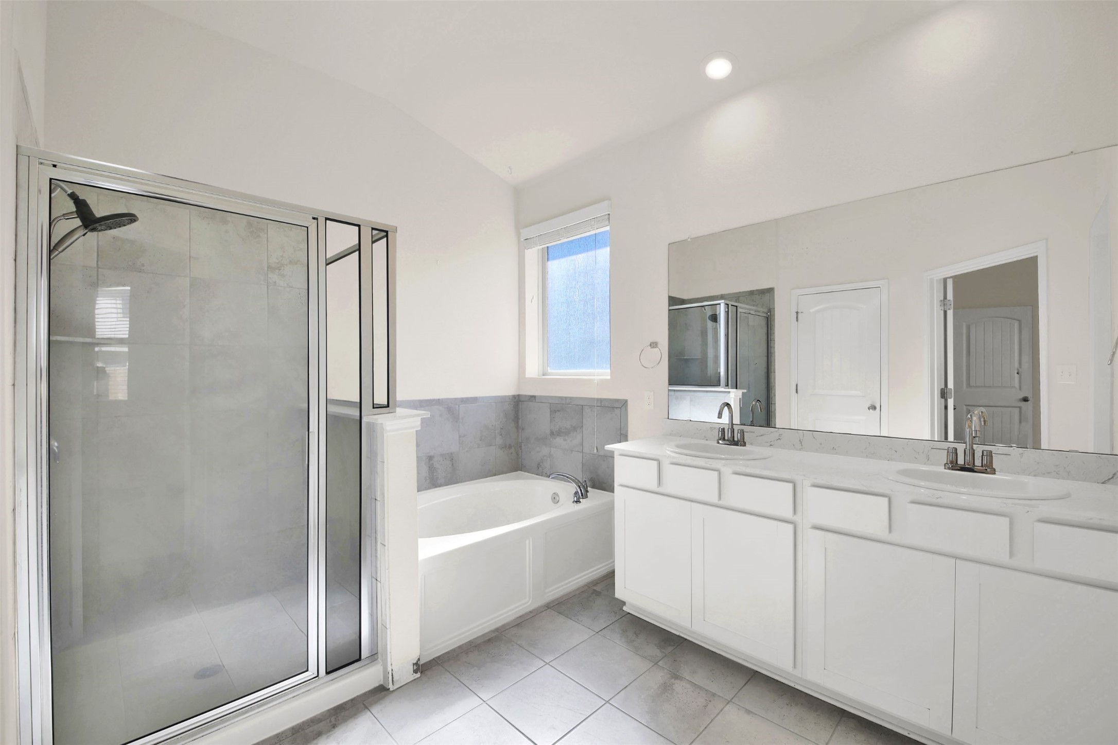 19032 Quebrada Drive Pflugerville, TX 78660 - Photo 22 of 29 Primary bathroom with a bath, double vanity, a stall shower, lofted ceiling, and light tile patterned flooring