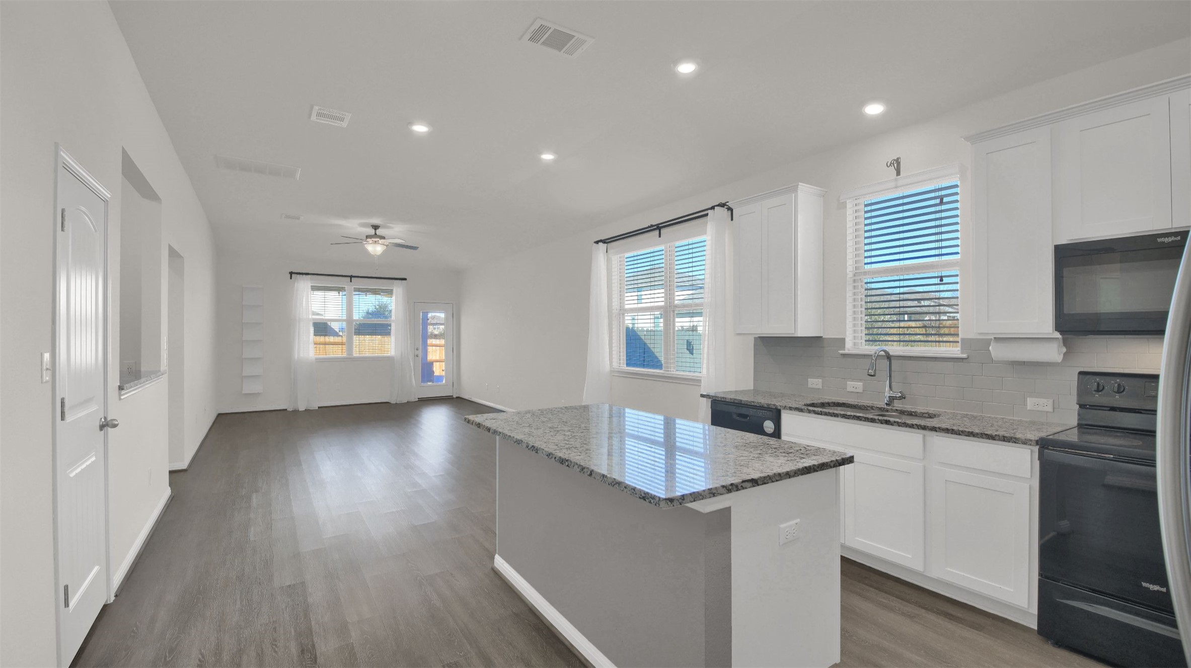 19032 Quebrada Drive Pflugerville, TX 78660 - Photo 4 of 29 Kitchen featuring dark stone counters, black appliances, white cabinets, a center island, and tasteful backsplash