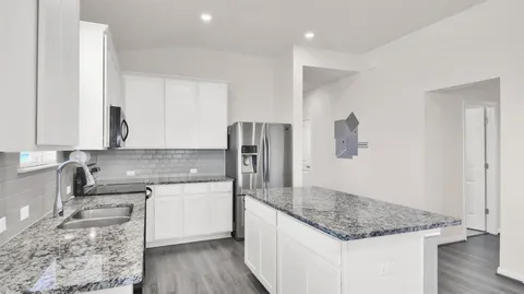 a kitchen with stainless steel appliances granite countertop a refrigerator a stove and a sink